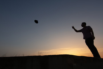 Fototapeta na wymiar silhouette of man throwing hat at sunset