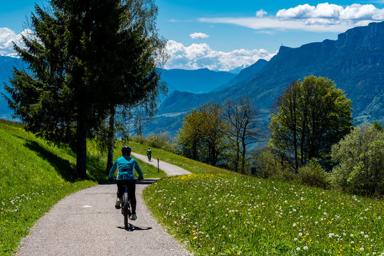 Radfahrer auf einer Anh&ouml;he zwischen Wiese und Wald mit Blick ins Tal