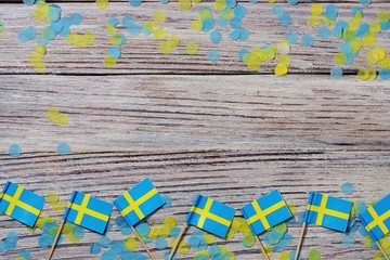 June 6 Sweden independence Day, the concept of the Day of memory of freedom and patriotism. Mini flags with paper confetti on wooden white background. place for text. copy space.