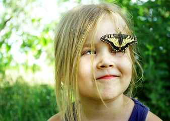 Butterfly sitting on a child. Child with a butterfly. Butterfly machaon on a little girl. Selective focus. Swallowtail butterfly, Papilio machaon.