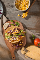 Traditional mexican taco with chicken and vegetables on wooden table. Latin american food.