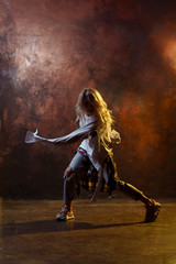 Fototapeta na wymiar Photo of dancing blonde girl in torn blue jeans on brown background