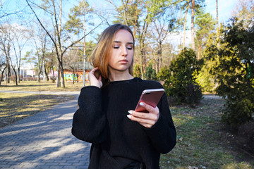 Young cute girl with mobile phone in city Park.