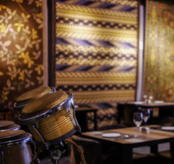 Bongo drums in empty restaurant with silk rug on the wall