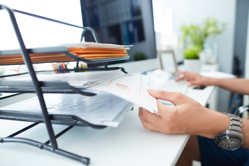 Close-up of a man's hand pulling files from office shelves.