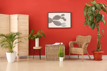 Stylish interior of room with wicker and wooden furniture near color wall