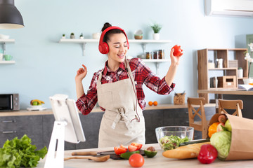 Beautiful woman listening to music in kitchen at home