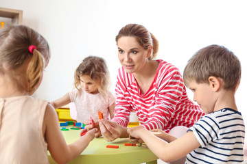 Obraz na płótnie Canvas Nursery teacher with cute little children in kindergarten