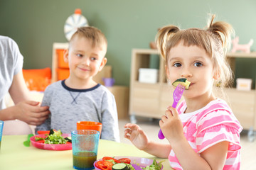 Cute little children eating tasty lunch in kindergarten
