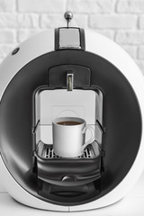 Modern coffee machine on table near white wall