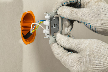 electrician puts an electrical outlet into the socket box