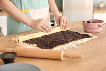 Woman preparing tasty pastry with poppy seeds at table