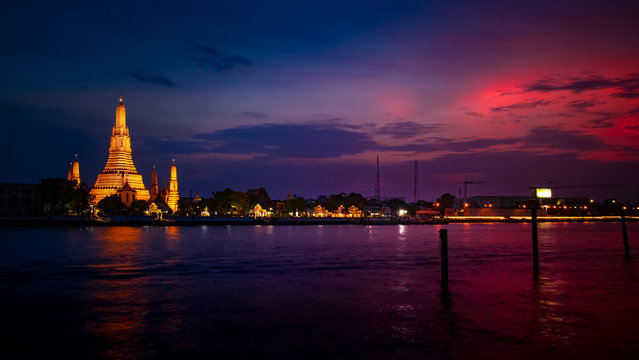 View of beautiful Wat Arun Rajvararam or Wat Arun or Wat Makok at waterfront of the Chao Phraya River in twilight,Which is historical significance and famous tourist destination of Bangkok,Thailand.