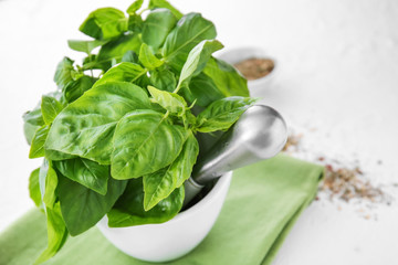Mortar with fresh basil on white table