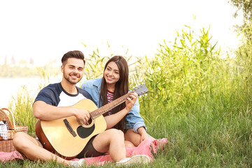 Young couple with guitar on picnic in park