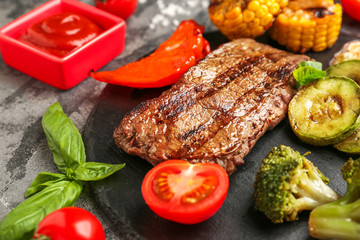 Tasty grilled meat and vegetables  on slate plate, closeup