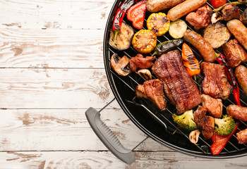 Grill with tasty cooked meat and vegetables on wooden background