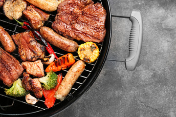 Grill with tasty cooked meat and vegetables on grey background
