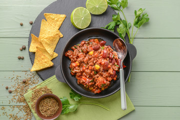 Frying pan with tasty chili con carne on wooden table