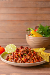 Plate with tasty chili con carne on wooden table