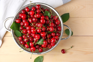 Colander with ripe cherry on wooden background