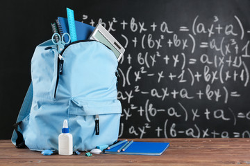 School backpack with stationery on table in classroom