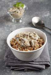 Buckwheat and quinoa porridge served with mushrooms in white vegan sauce. Healthy vegetarian food concept.