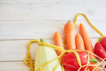 String bag with various fresh vegetables on white textured background. Organic eco bio products...