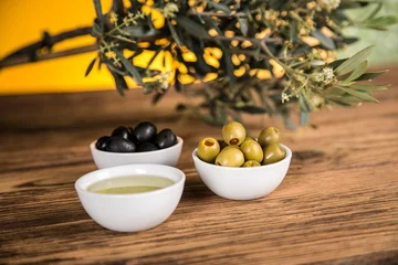 Foto op Plexiglas Olive oil, olive tree and green and black olives on a wooden table © dianaduda