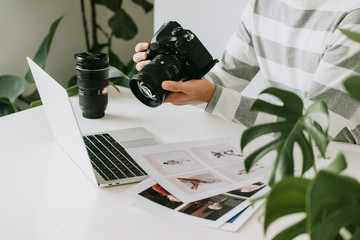 male photographer holding digital camera above the desk in his photo studio