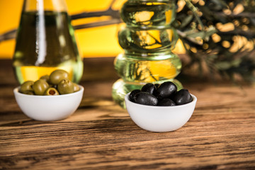Olive oil, olive tree and green and black olives on a wooden table