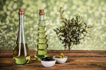 Olive oil, olive tree and green and black olives on a wooden table