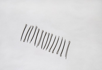 black metal hairpins lie in an even row diagonally on a white background