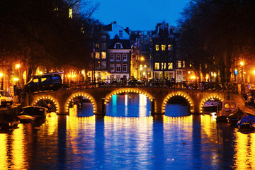 Fototapeta premium Illuminated bridge and historical buildings in Amsterdam, Netherlands at night