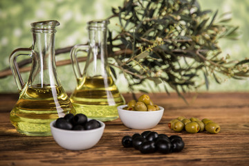 Obraz na płótnie Canvas Olive oil, olive tree and green and black olives on a wooden table