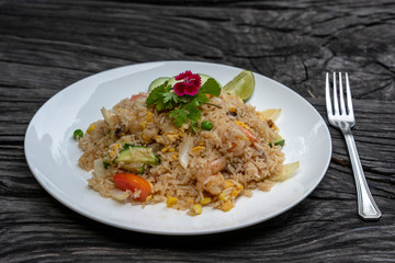 Fried rice with shrimps and vegetables in a white dish on an old wooden table, close up . Thai food , Thai cuisine