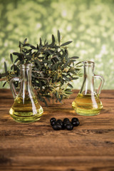 Olive oil and olive tree and black olives and bottles with olive on a wooden table