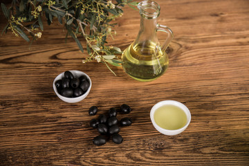 Olive oil and olive tree and black olives and bottles with olive on a wooden table