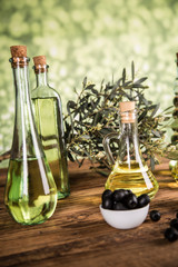 Olive oil, olive tree and green and black olives on a wooden table