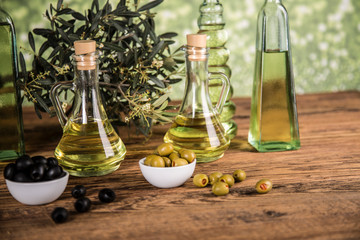 Olive oil, olive tree and green and black olives on a wooden table