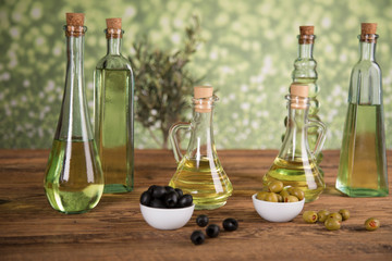 Olive oil, olive tree and green and black olives on a wooden table