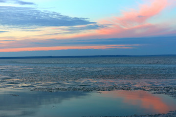Clear calm lake with ice floes drift on the water. Blue evening light and purple cloudy sky at the winter river or lake