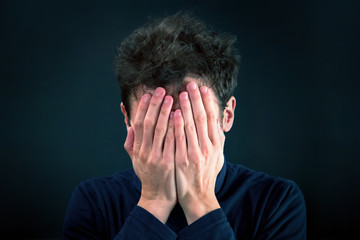 Man with problems covering his face. Emotional Stress: he's depressed or he feels shame for something