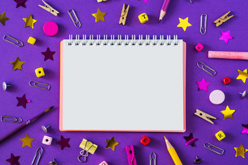 Multicolored school supplies on violet background with copy space.