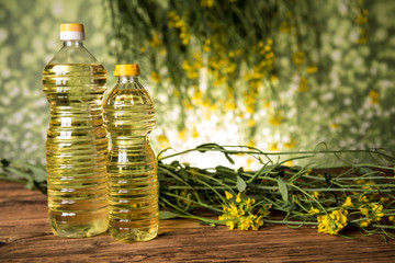 Rapeseed flowers and rapeseed oil in a bottle on the table