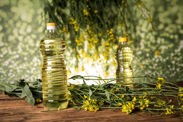 Rapeseed flowers and rapeseed oil in a bottle on the table