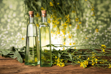 Rapeseed flowers and rapeseed oil in a bottle on the table