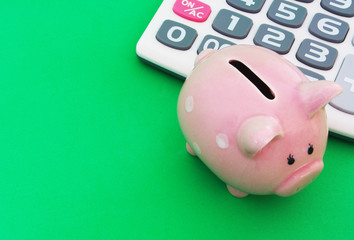Piggy bank and calculator on green background with room for text