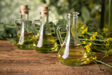 Rapeseed flowers and rapeseed oil in a bottle on the table