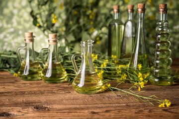 Rapeseed flowers and rapeseed oil in a bottle on the table